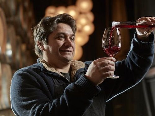 Portrait de notre oenologue Rodrigo Banto en train de verser du vin rouge dans un verre depuis une pipette. Nos conseils pour créer sa cave.
